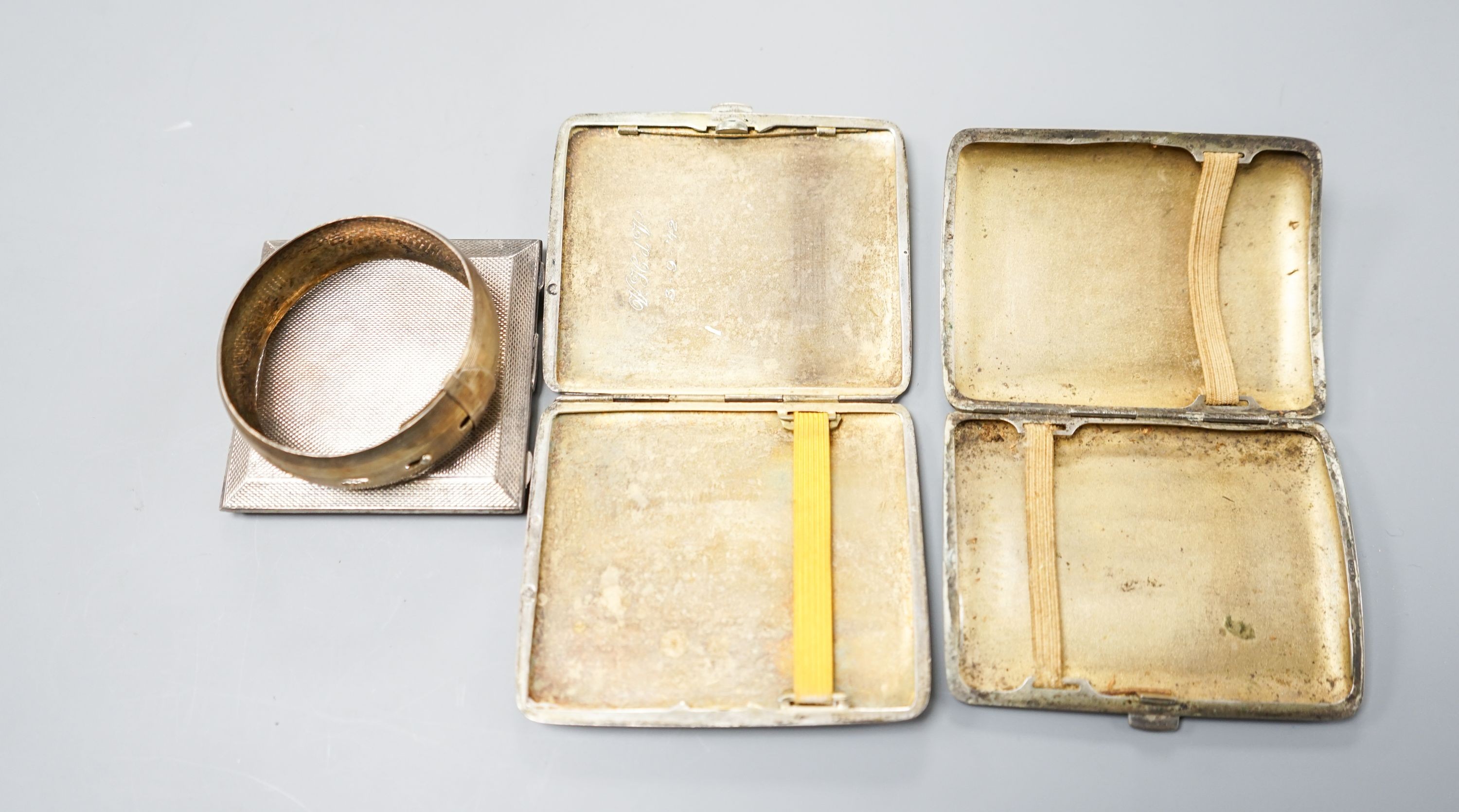 An 800 white metal and niello cigarette case,9cm, a Dutch gilt and white metal cigarette case, an engine-turned silver powder compact (a.f.) and a white metal bangle.